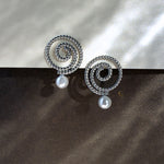 Silver Thaleia spiral earrings with pearl-like beads against dark shimmering background