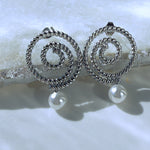 Thaleia silver spiral earrings with pearl-like drops on icy crystal surface