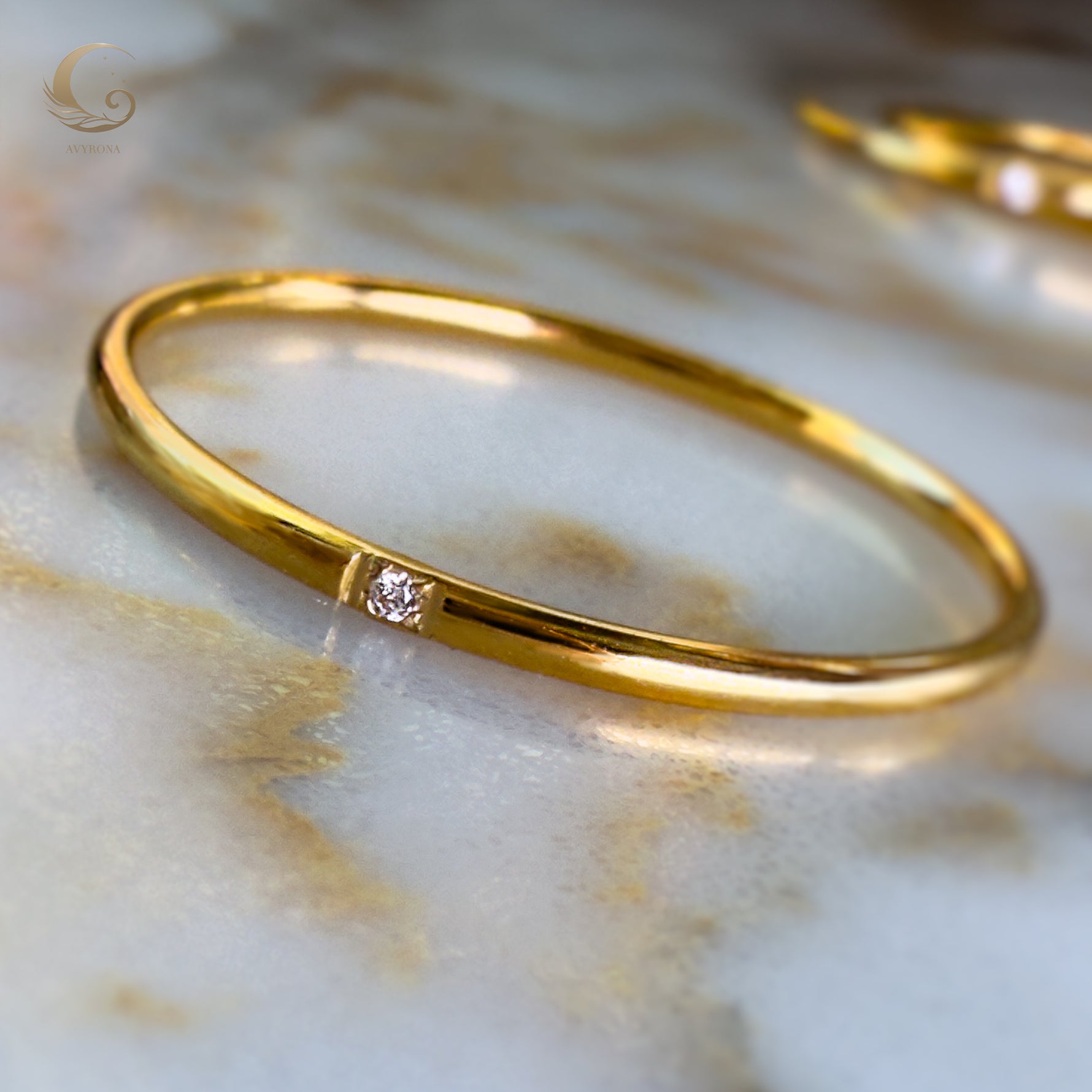 One minimalist gold ring with single zircon stone, close-up on marble