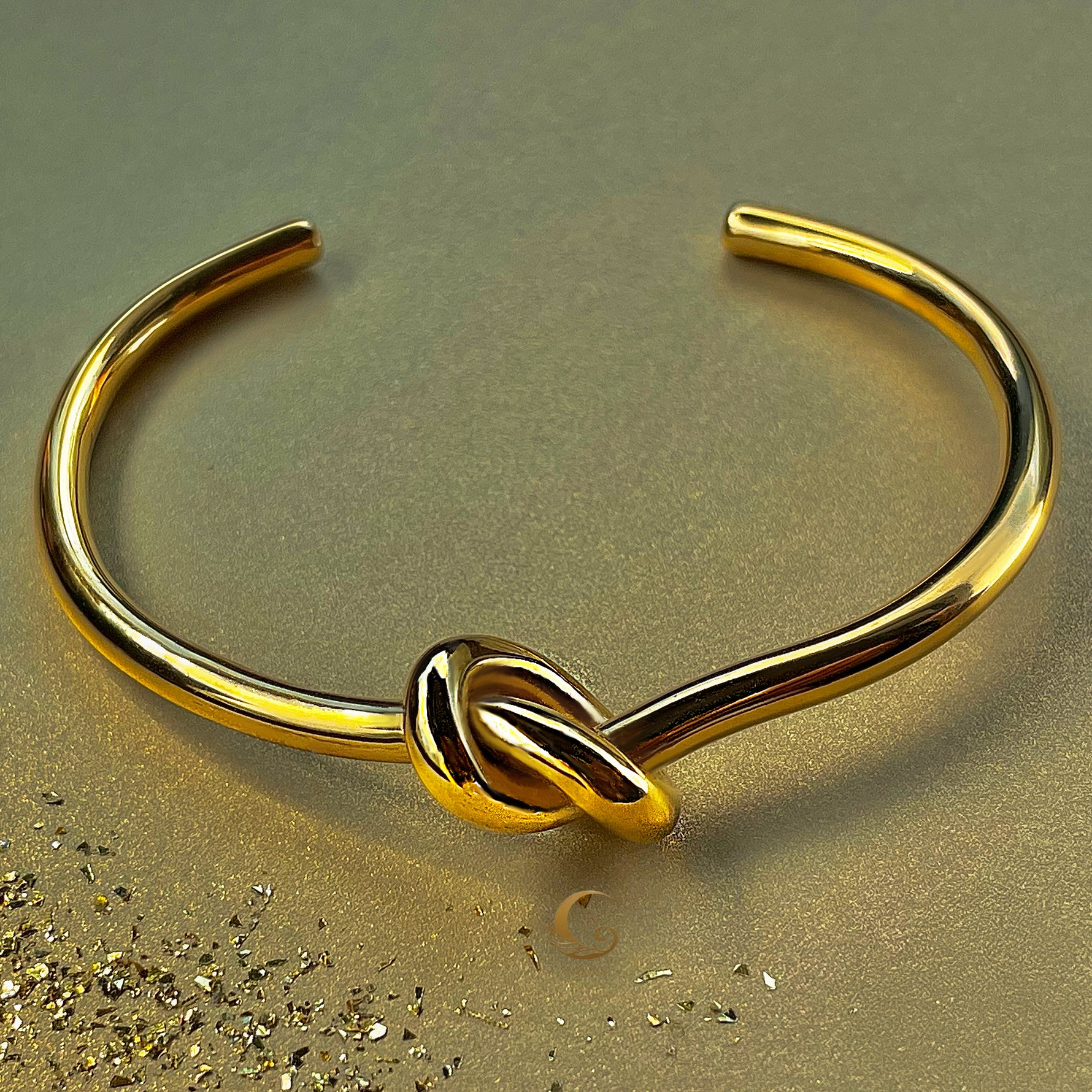 Elegant gold knot bracelet on golden background, open bangle design symbolizing unity – Avyrona