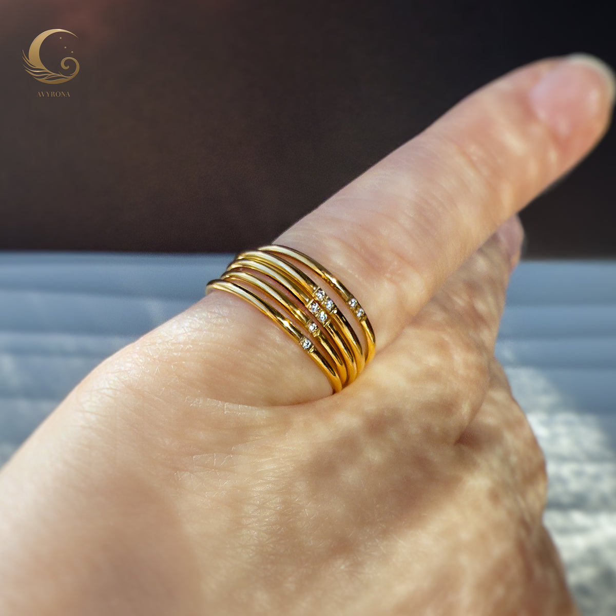 Hand wearing multiple gold zircon bands stacked together