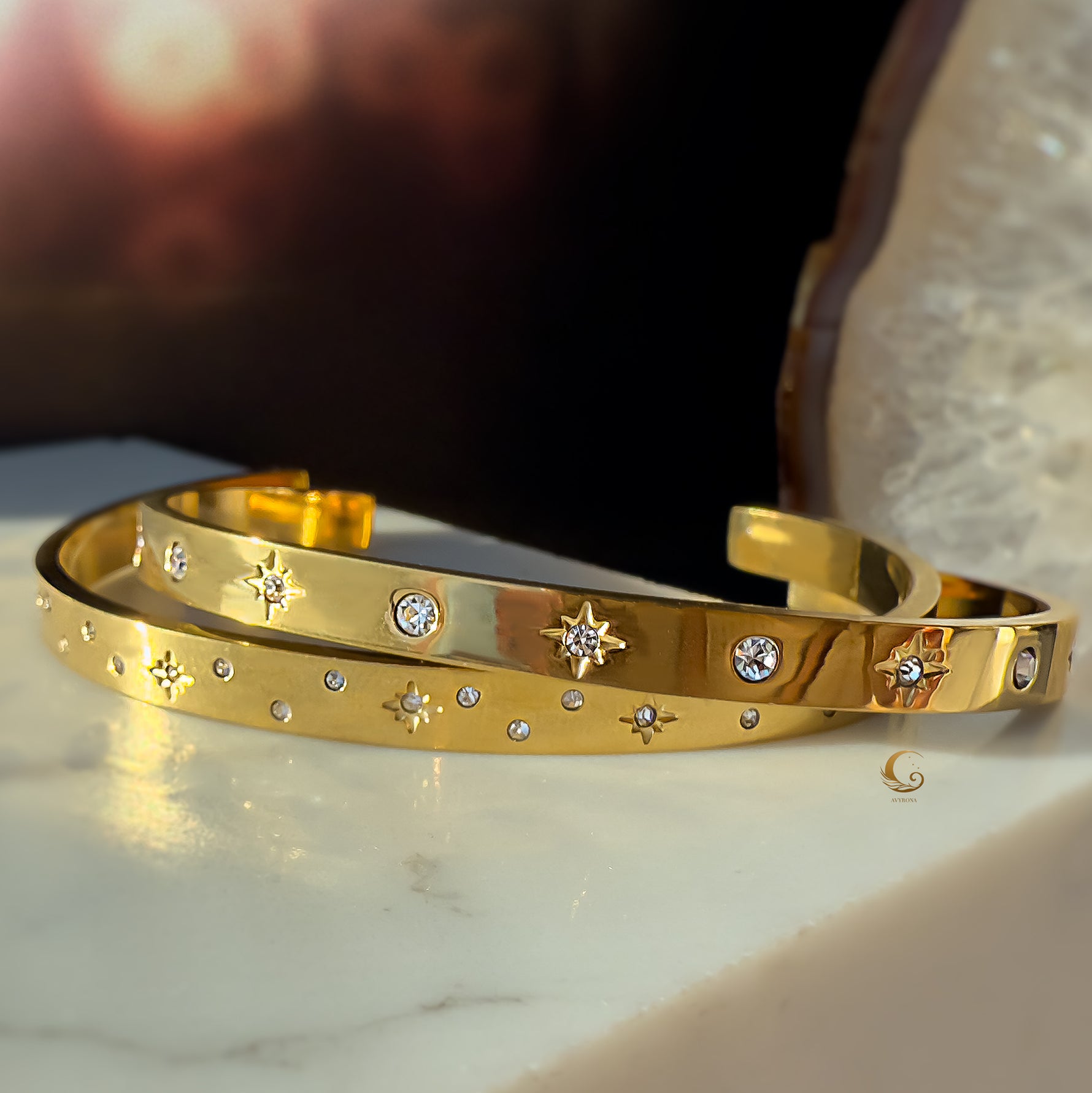 Side view of celestial gold bracelets with 3A cubic zirconia, leaning on a marble slab.