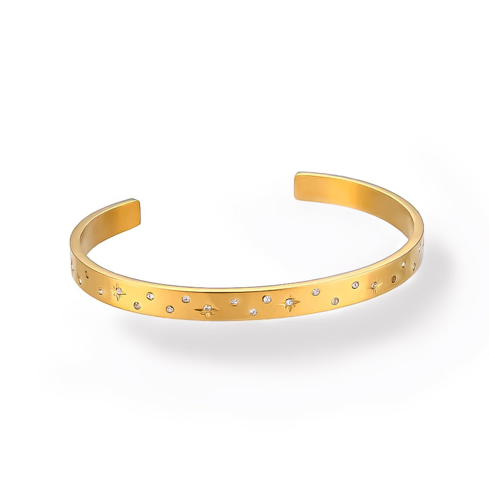 Minimalist celestial bracelet with star engravings and stones, photographed on a white background.