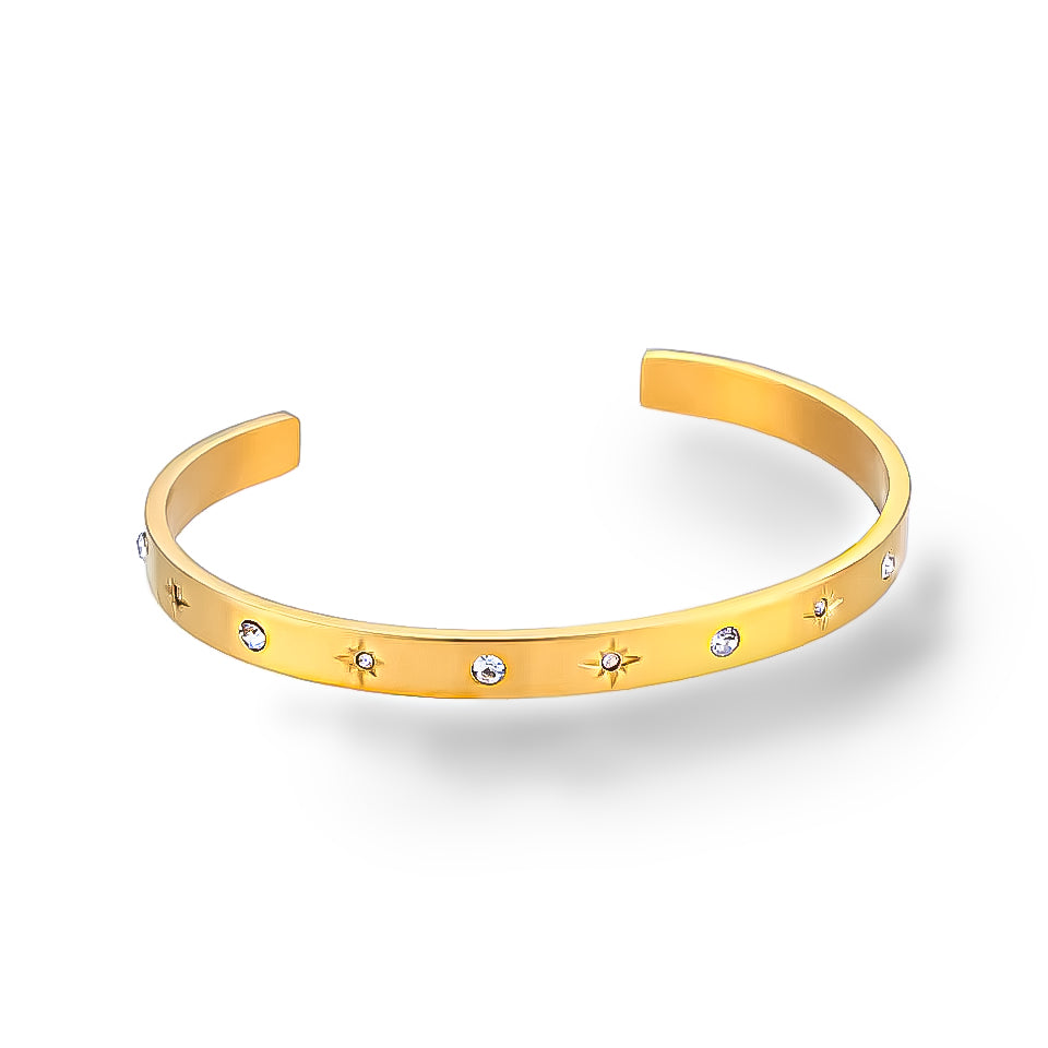 Angled view of a single gold cuff bracelet with cubic zirconia and celestial motifs on white background.