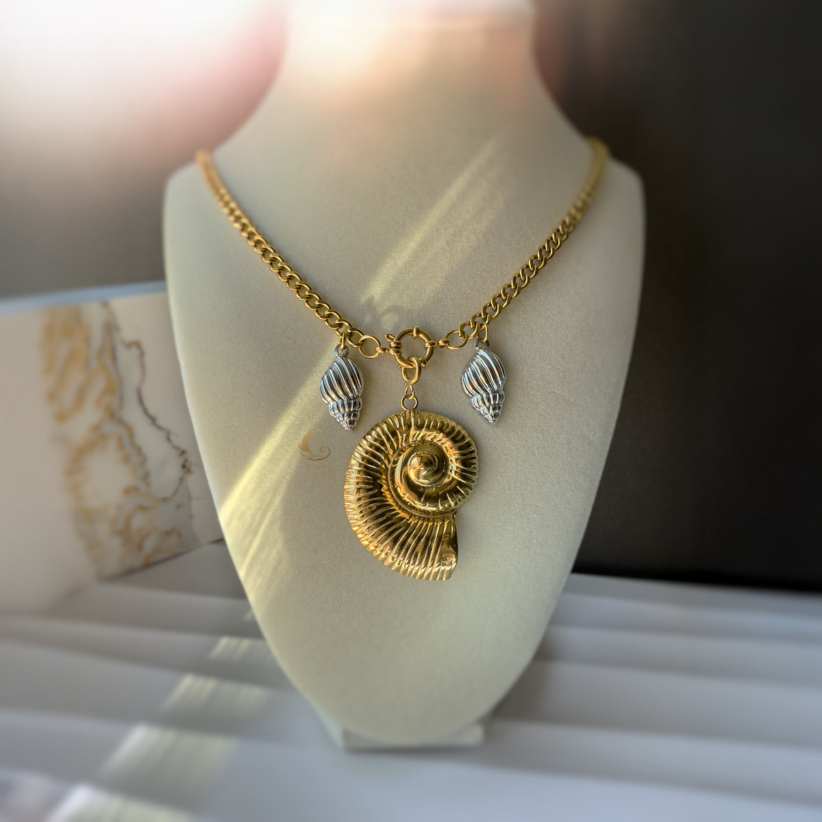 The Thalassa necklace displayed on a bust, showcasing its elegant drape and statement shell centerpiece.