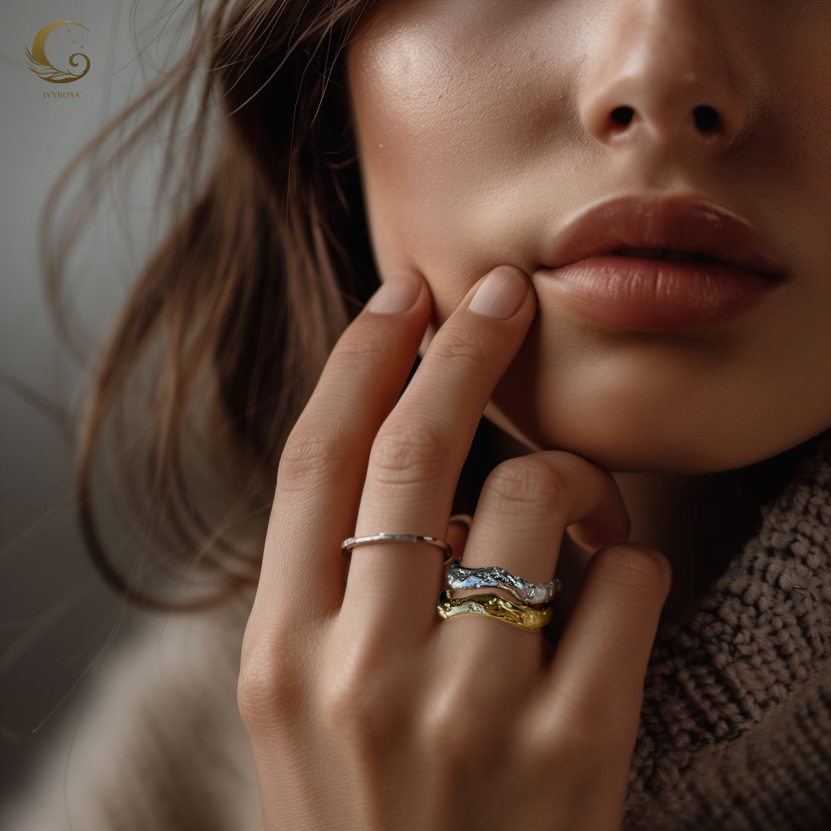 Close-up of a woman's hand wearing the Wave ring in gold and silver tones, highlighting its organic, flowing shape.