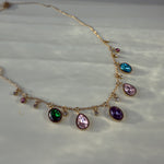 Multicolor charm necklace laid flat, showing full strand and golden chain