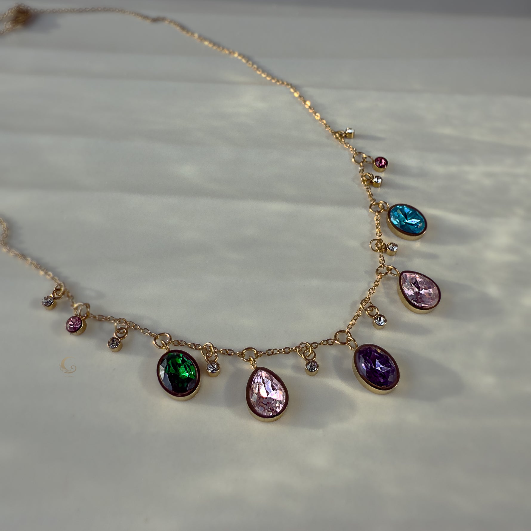 Multicolor charm necklace laid flat, showing full strand and golden chain