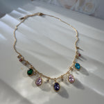 Full view of Zaria necklace with colorful stones and extender on white satin