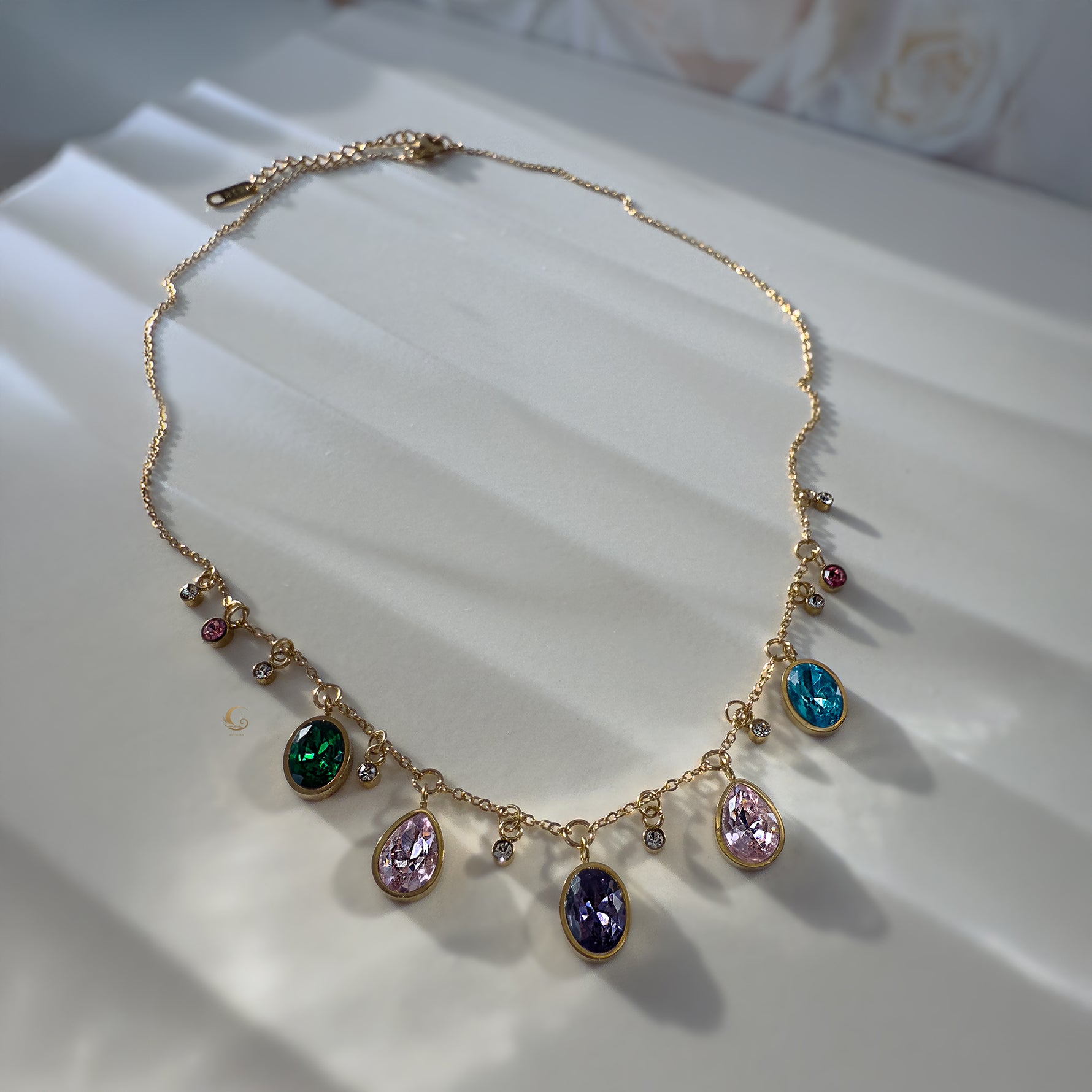 Full view of Zaria necklace with colorful stones and extender on white satin