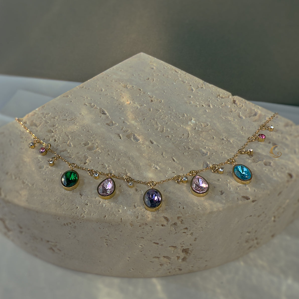 Zaria necklace with multicolor stones placed on textured white stone display